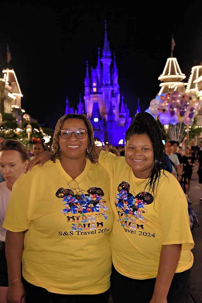 Two S&S Travel guests smiling in front of a brightly lit castle