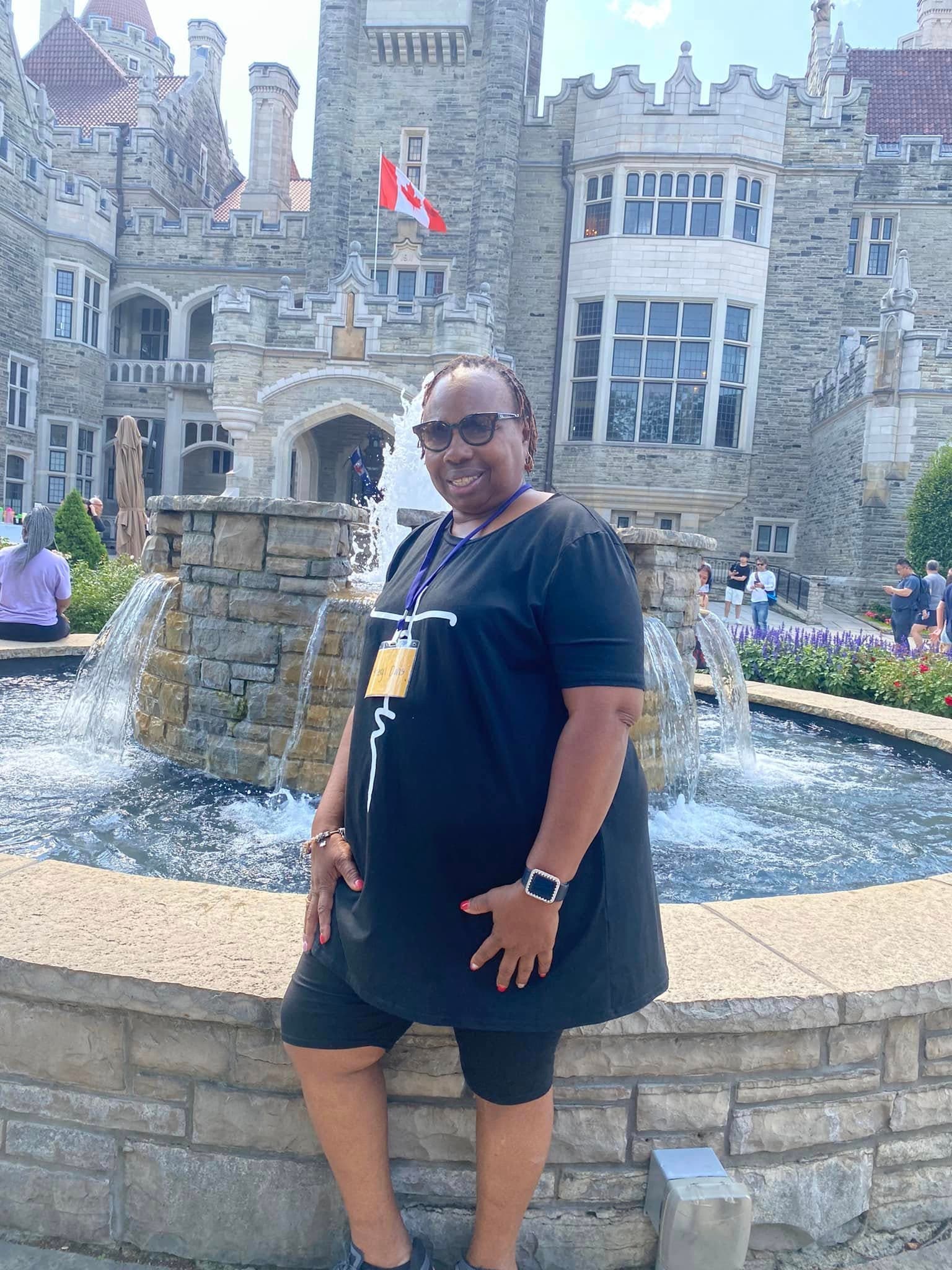 An S&S Travel guest smiling in front of a castle and fountain