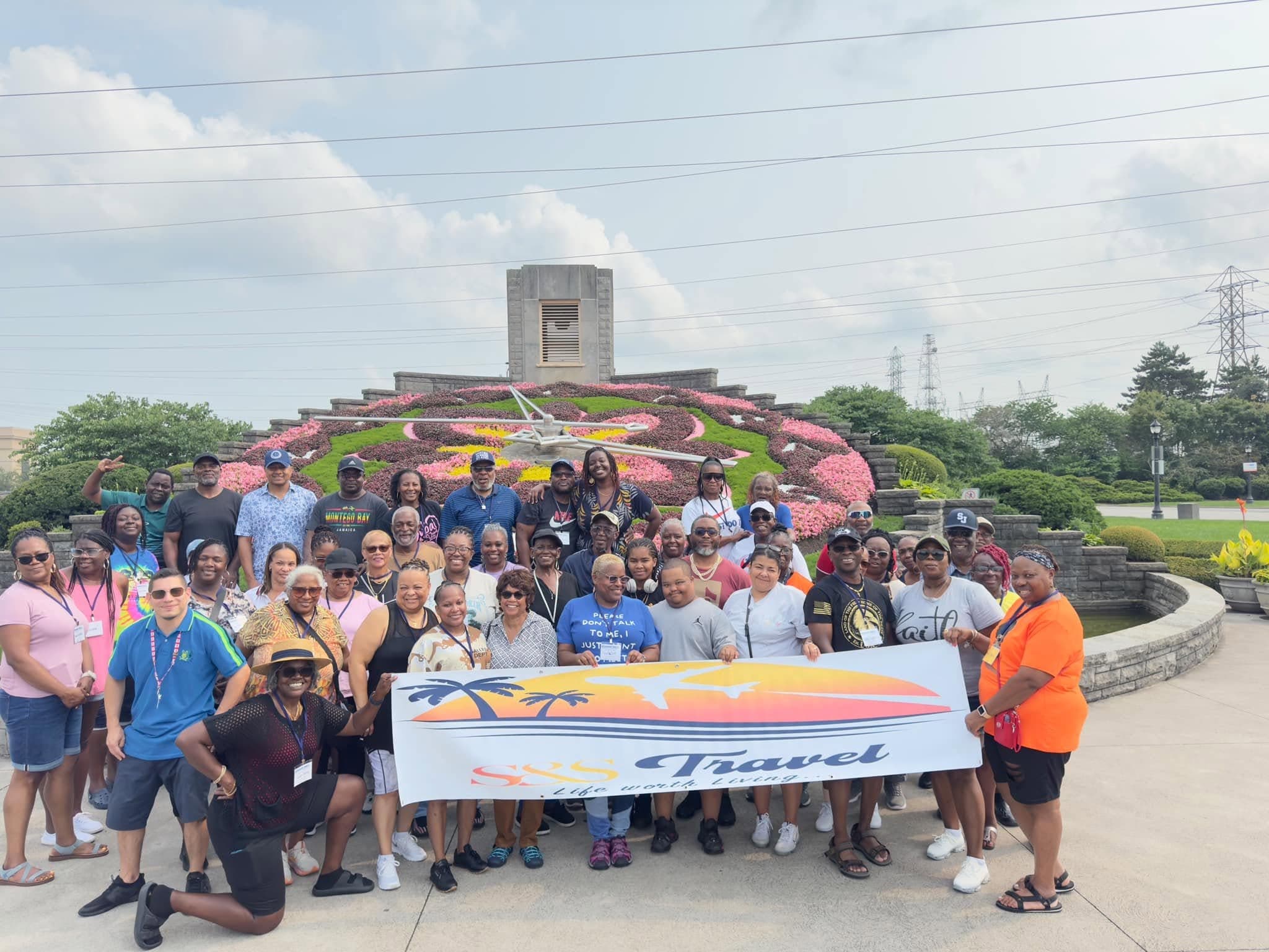 A large S&S Travel group smiling together with the agency banner